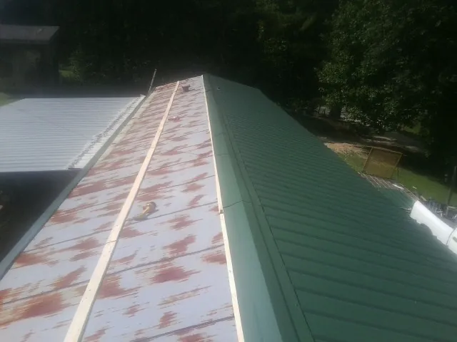 Old rusted panels beside newly installed green metal roofing — Wind Damage Roof Repair by Roofing Brothers in Rockton